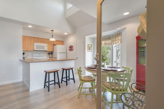 dining area with light wood-type flooring, lofted ceiling, and sink