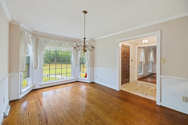 unfurnished dining area featuring an inviting chandelier, crown molding, dark tile floors, and a textured ceiling