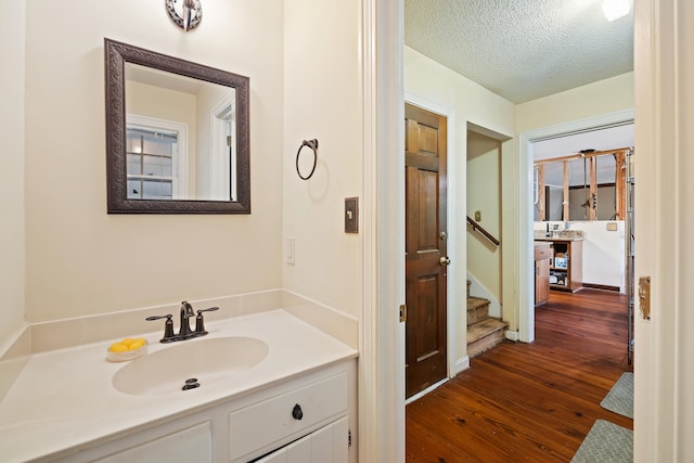 bathroom featuring a textured ceiling, vanity with extensive cabinet space, and hardwood / wood-style flooring