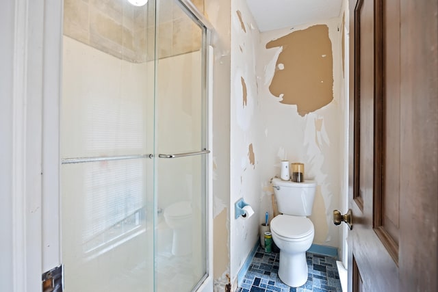 bathroom with toilet, tile floors, and a shower with door