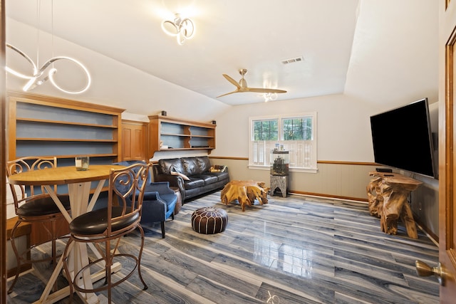 living room featuring ceiling fan with notable chandelier, vaulted ceiling, and dark wood-type flooring