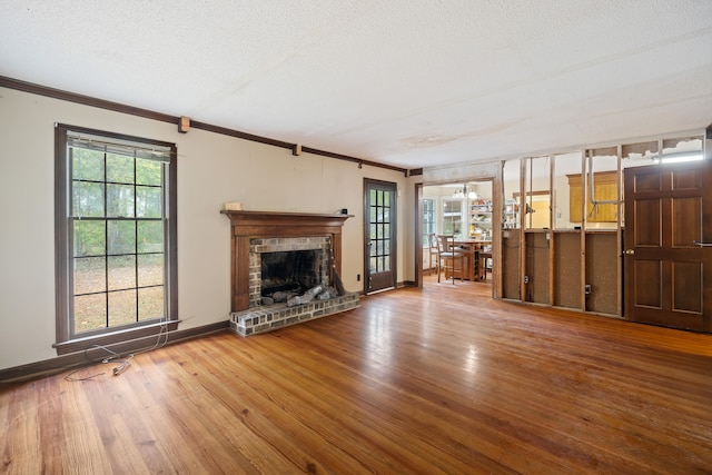 unfurnished living room with dark hardwood / wood-style floors, a brick fireplace, a textured ceiling, and a wealth of natural light