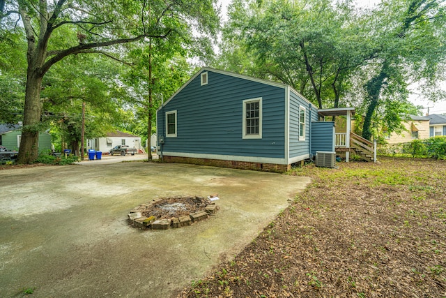 view of side of property featuring an outdoor fire pit, central AC, and a patio