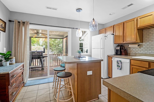 kitchen with backsplash, white appliances, a kitchen island, hanging light fixtures, and light tile patterned flooring