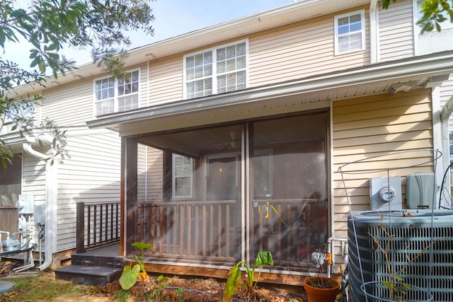 rear view of property with central AC unit and a sunroom