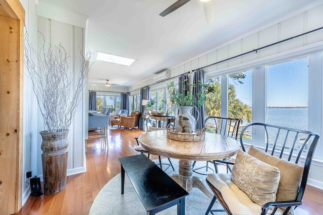 sunroom / solarium featuring a water view, a skylight, and a wall mounted air conditioner