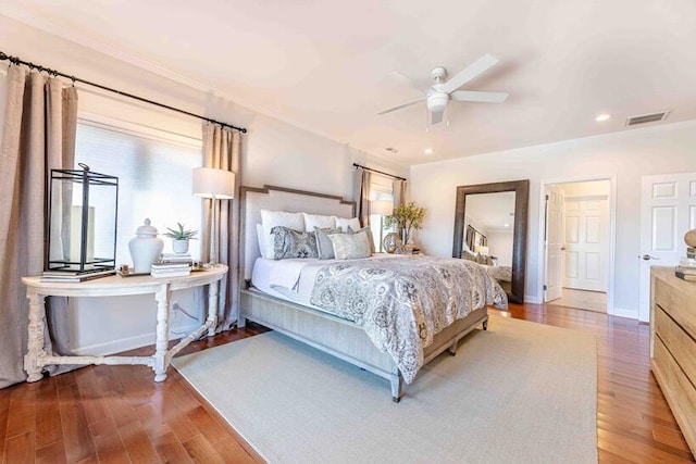 bedroom featuring baseboards, visible vents, wood finished floors, and ornamental molding