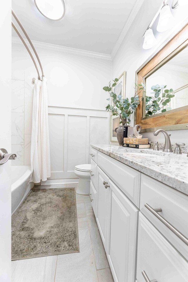 bathroom with crown molding, toilet, vanity, a decorative wall, and shower / bath combo with shower curtain