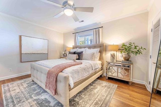bedroom with baseboards, visible vents, wood finished floors, and ornamental molding