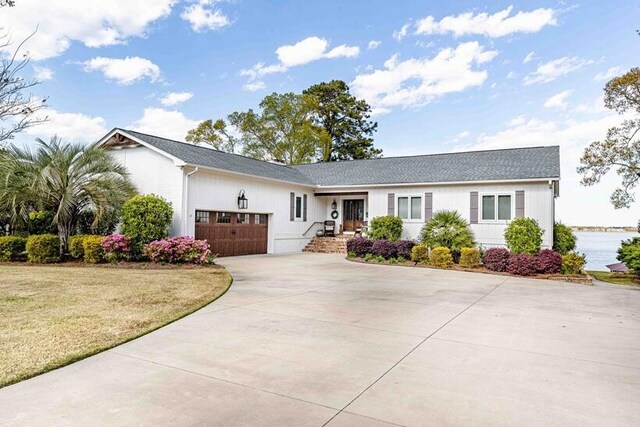 ranch-style house featuring a front lawn, driveway, a shingled roof, and a garage