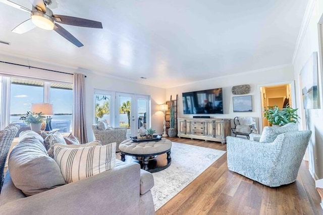 living area with visible vents, ornamental molding, ceiling fan, and wood finished floors
