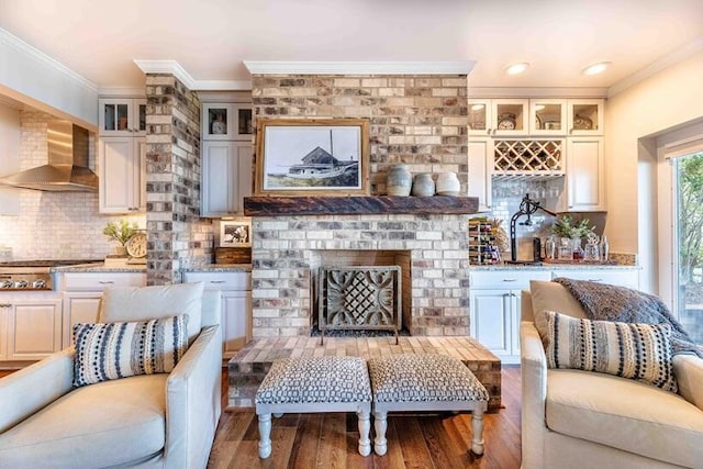living room with a fireplace, wood finished floors, and ornamental molding