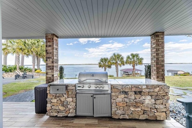 view of patio featuring area for grilling, a water view, and exterior kitchen