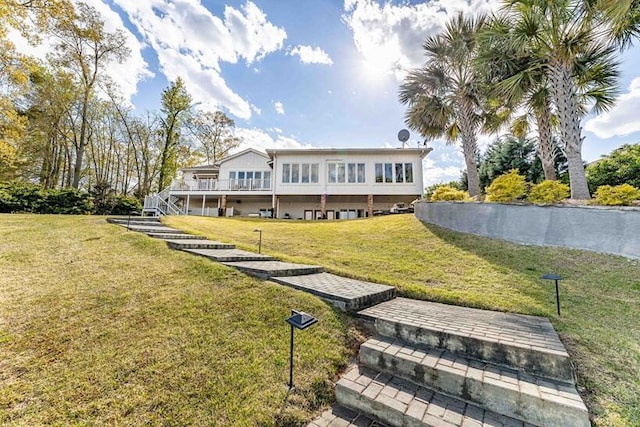 rear view of property with a lawn, stairway, and a deck