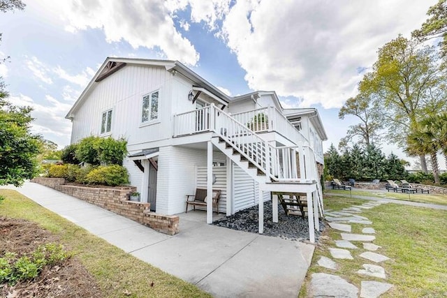 view of side of property featuring a lawn, stairway, and a patio area
