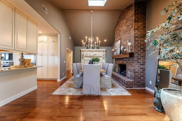 dining area with a fireplace, visible vents, light wood-style flooring, and an inviting chandelier