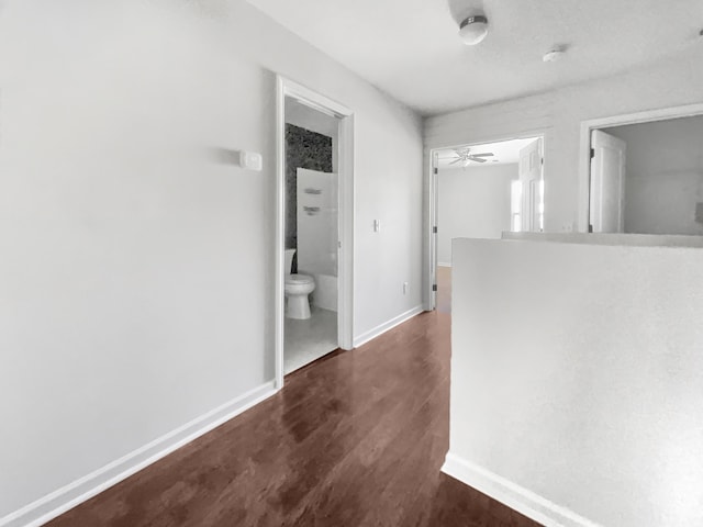 corridor featuring dark wood-type flooring and baseboards