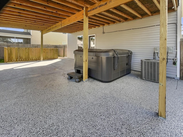 view of patio featuring fence, cooling unit, and a hot tub