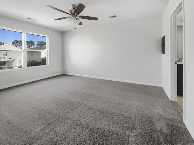 carpeted spare room featuring ceiling fan, visible vents, and baseboards