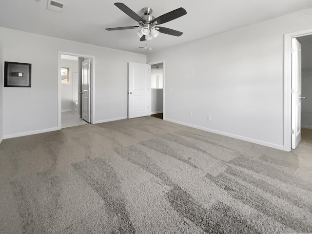 unfurnished bedroom featuring electric panel, baseboards, visible vents, ensuite bath, and carpet flooring