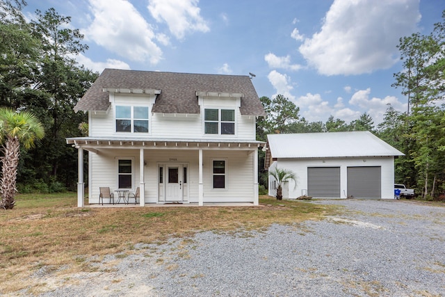 view of front facade featuring a garage, covered porch, and an outbuilding