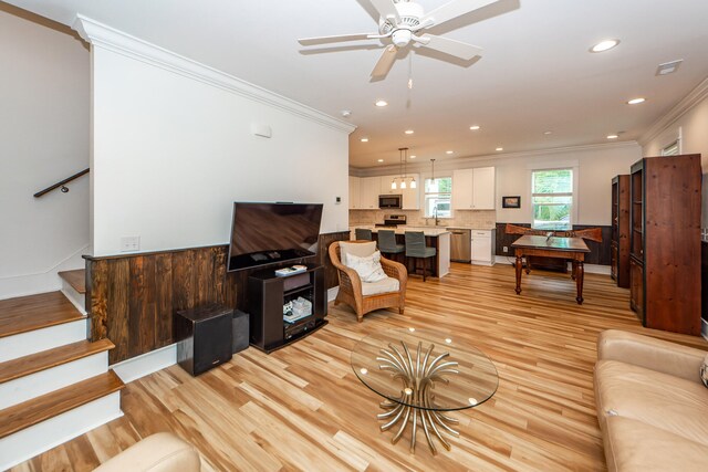 living room featuring light wood-type flooring, crown molding, sink, and ceiling fan