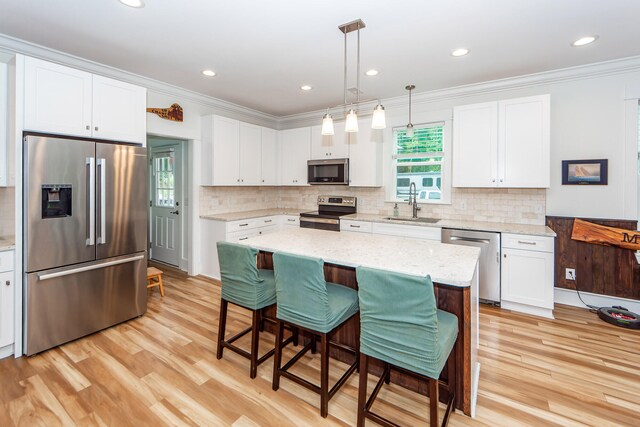 kitchen with a kitchen island, light stone countertops, light hardwood / wood-style floors, stainless steel appliances, and white cabinetry