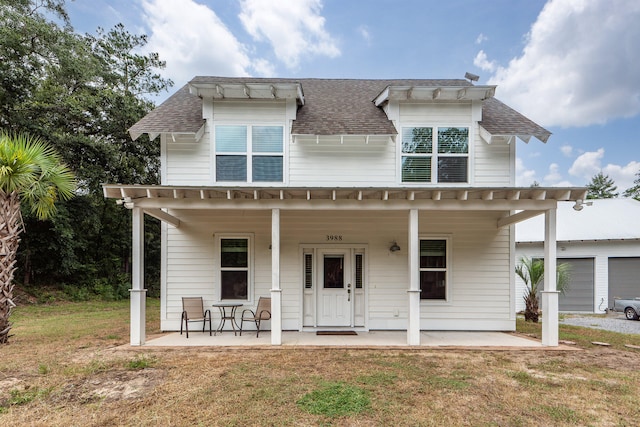 view of front of house featuring a garage, a front yard, covered porch, and an outbuilding