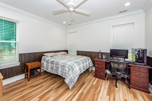 bedroom with wood walls, ceiling fan, light hardwood / wood-style floors, and crown molding