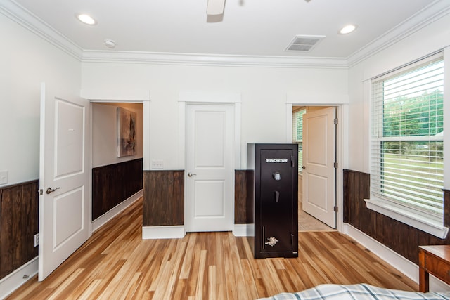 interior space with ceiling fan, ornamental molding, light wood-type flooring, and wooden walls