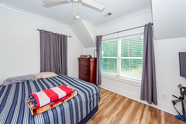 bedroom featuring light wood-type flooring, multiple windows, ceiling fan, and ornamental molding