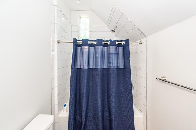 bathroom with lofted ceiling, shower / bath combination with curtain, and toilet