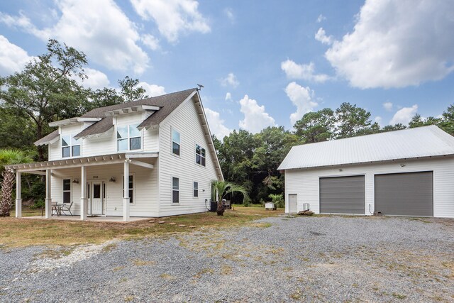 view of side of home featuring an outdoor structure, a garage, and a porch