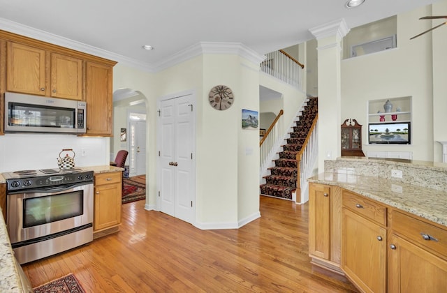 kitchen with appliances with stainless steel finishes, arched walkways, light wood-type flooring, and crown molding