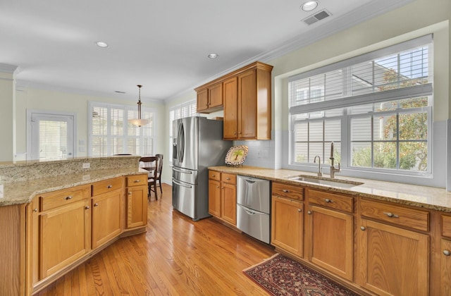 kitchen featuring light wood finished floors, visible vents, appliances with stainless steel finishes, ornamental molding, and a sink