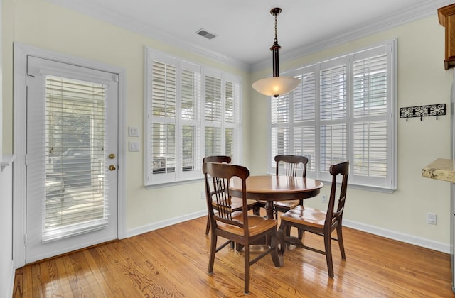 dining area with ornamental molding, visible vents, light wood-style floors, and baseboards