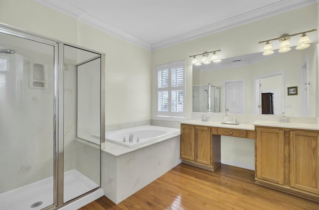 bathroom featuring double vanity, wood finished floors, a garden tub, crown molding, and a shower stall