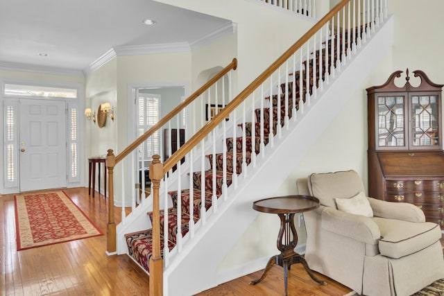 entryway with ornamental molding, stairway, wood-type flooring, and baseboards