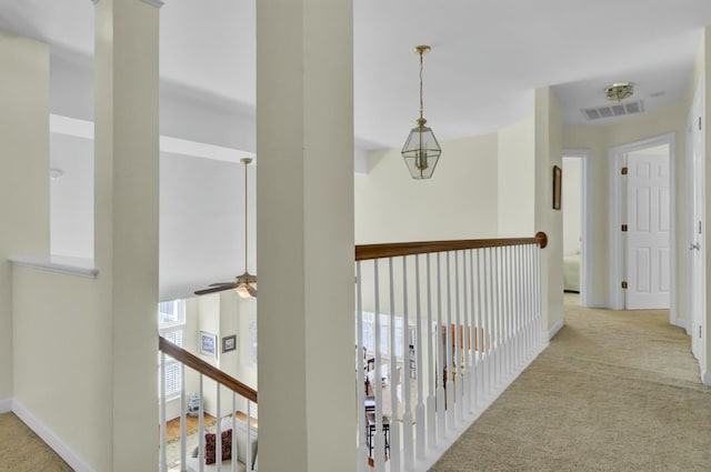 hall featuring carpet floors, visible vents, and baseboards