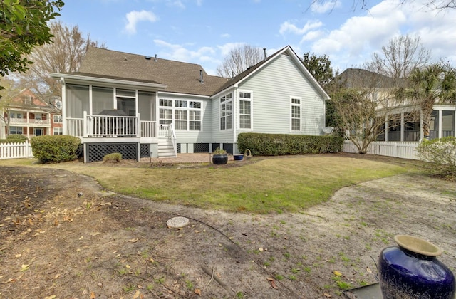 rear view of house with a sunroom, fence, and a lawn