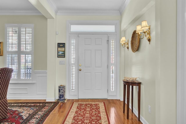 foyer entrance featuring a wainscoted wall, ornamental molding, and wood finished floors