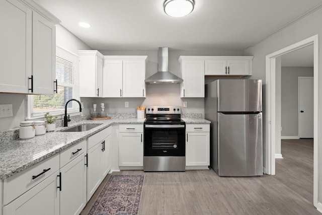 kitchen featuring sink, wall chimney exhaust hood, light hardwood / wood-style floors, white cabinets, and appliances with stainless steel finishes