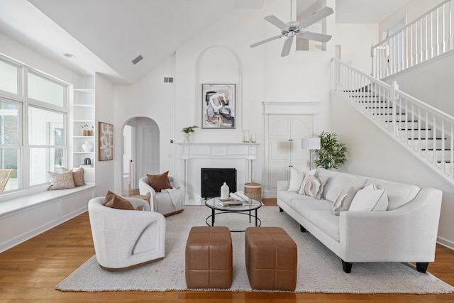 living room featuring arched walkways, stairs, wood finished floors, and visible vents