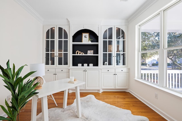 interior space featuring light wood-style flooring, baseboards, and crown molding