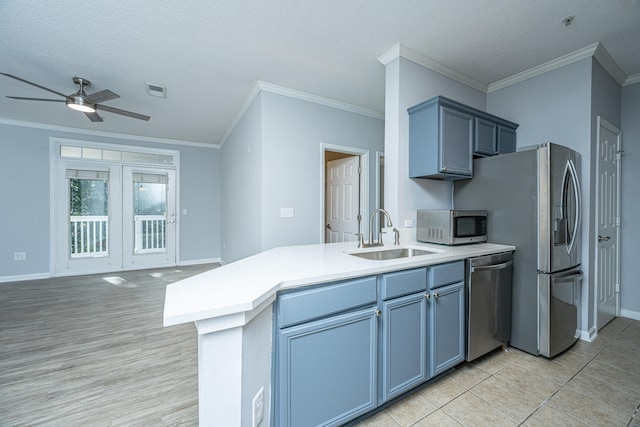 kitchen featuring stainless steel appliances, ornamental molding, sink, and a textured ceiling