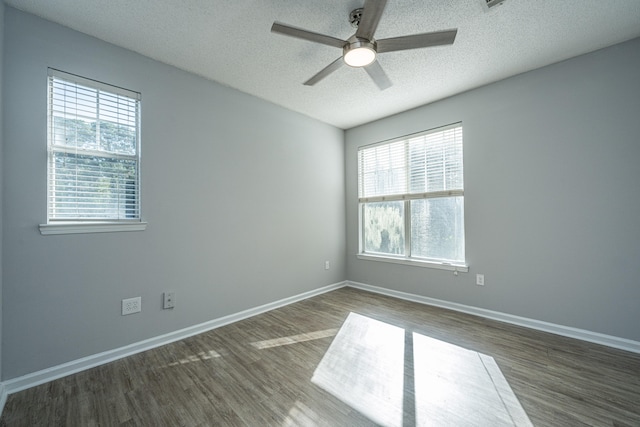 empty room featuring a textured ceiling, ceiling fan, dark hardwood / wood-style floors, and plenty of natural light