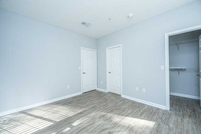 unfurnished bedroom featuring a spacious closet and hardwood / wood-style flooring