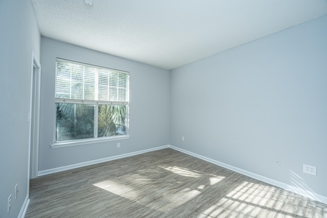 empty room featuring a textured ceiling and dark wood-type flooring