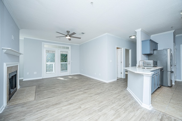 kitchen with light hardwood / wood-style floors, ornamental molding, a tiled fireplace, and sink