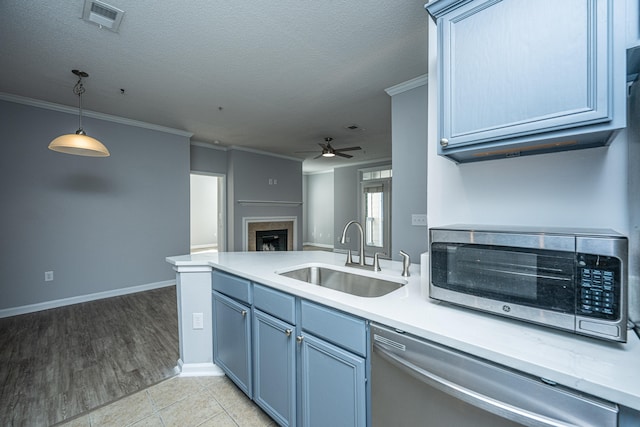 kitchen with stainless steel appliances, ornamental molding, sink, pendant lighting, and light wood-type flooring